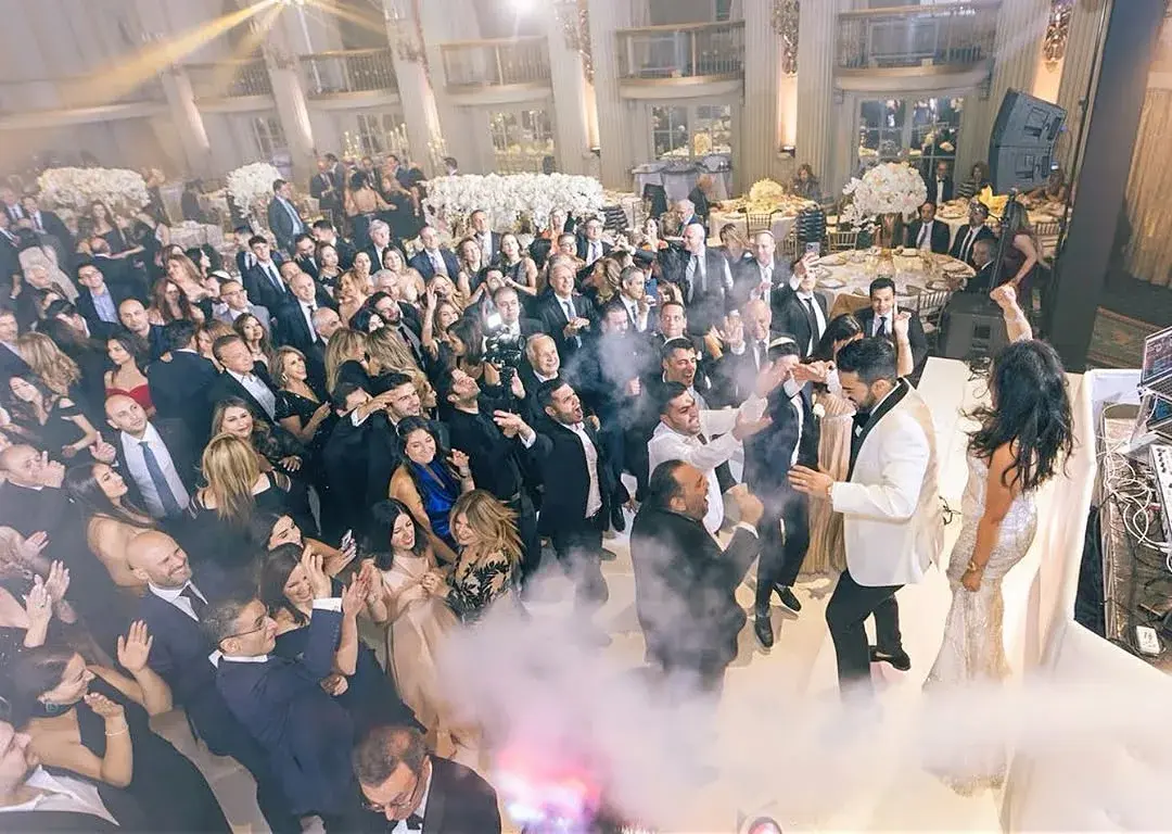 Newlyweds entering a packed dance floor as guests cheer under haze and lighting at a luxury Los Angeles wedding reception